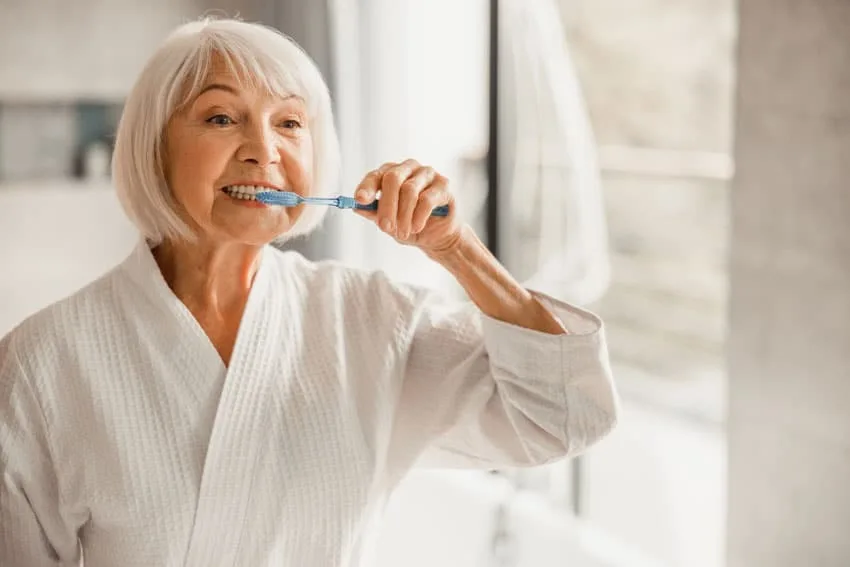 A patient carefully caring for their smile after dental implant surgery