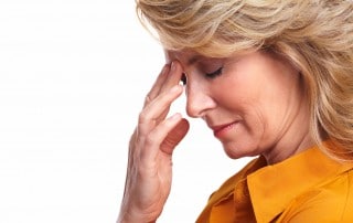 Woman with a migraine holds her hand to her head