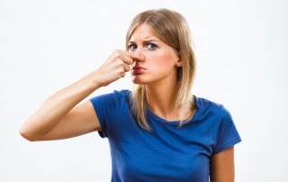 Young woman holding her nose together because of the horrible smell