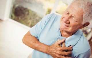 Older man grabs his chest while having a heart attack