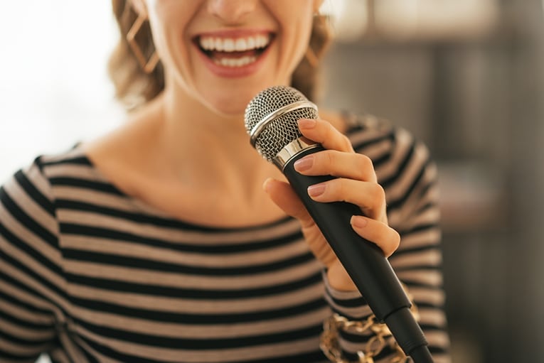 Closeup on young woman singing with microphone
