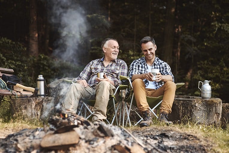middle aged father and son enjoying a camping trip by the fire