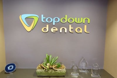 top down dental sign hanging above shelf with awards and plant