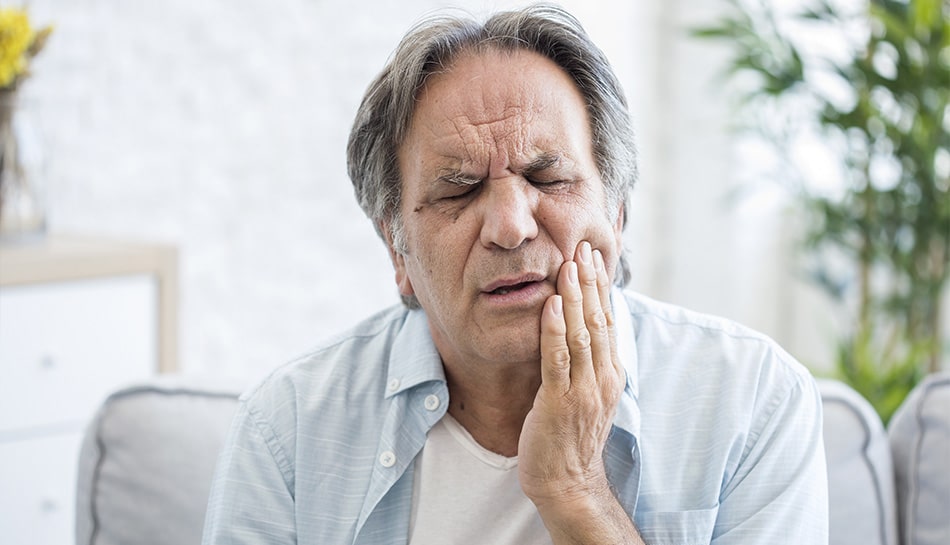 Man holding his jaw in discomfort. 