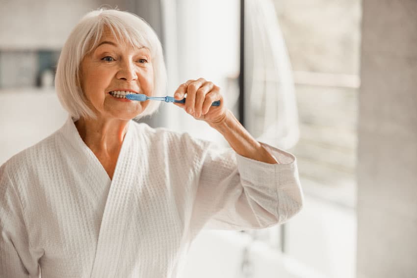 senior woman gently brushing her teeth
