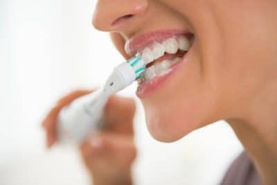 adult brushing their teeth with an electric tooth brush