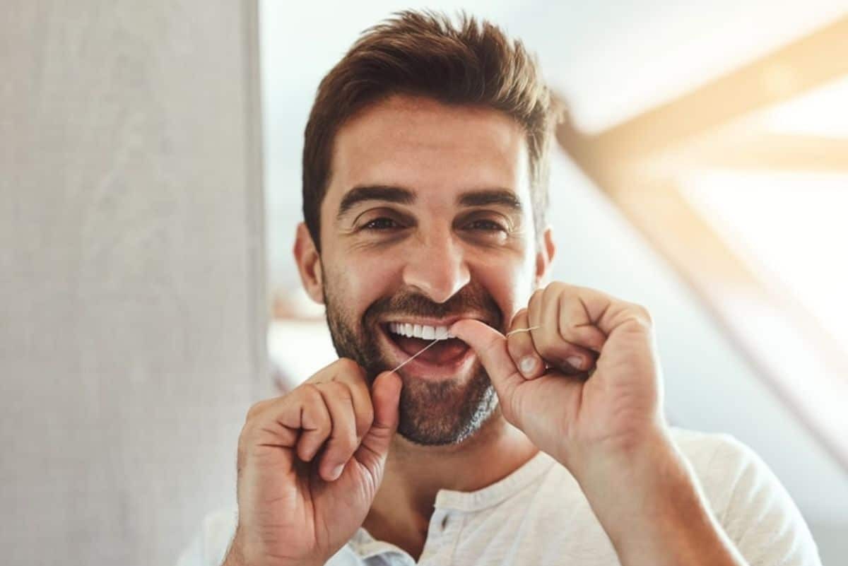 man-flossing-and-smiling-with-teeth