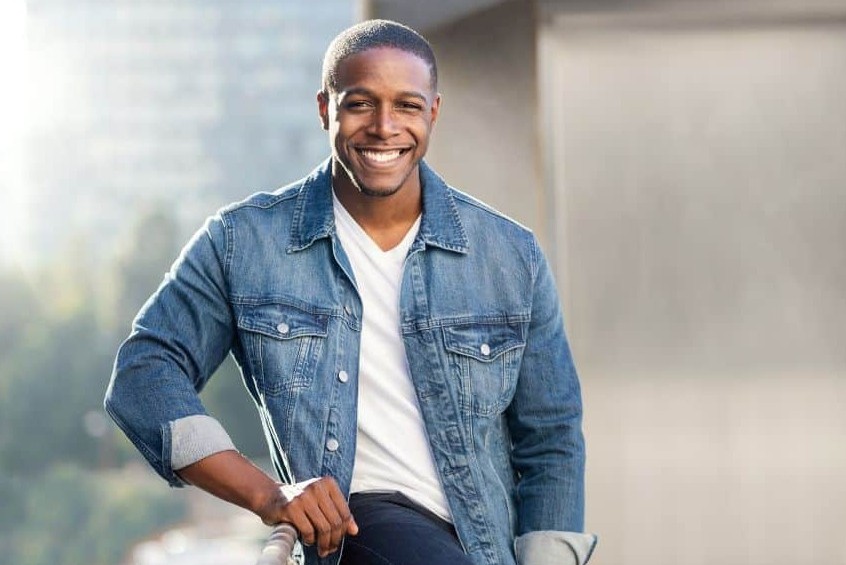 Man in denim jacket leaning on rail and smiling