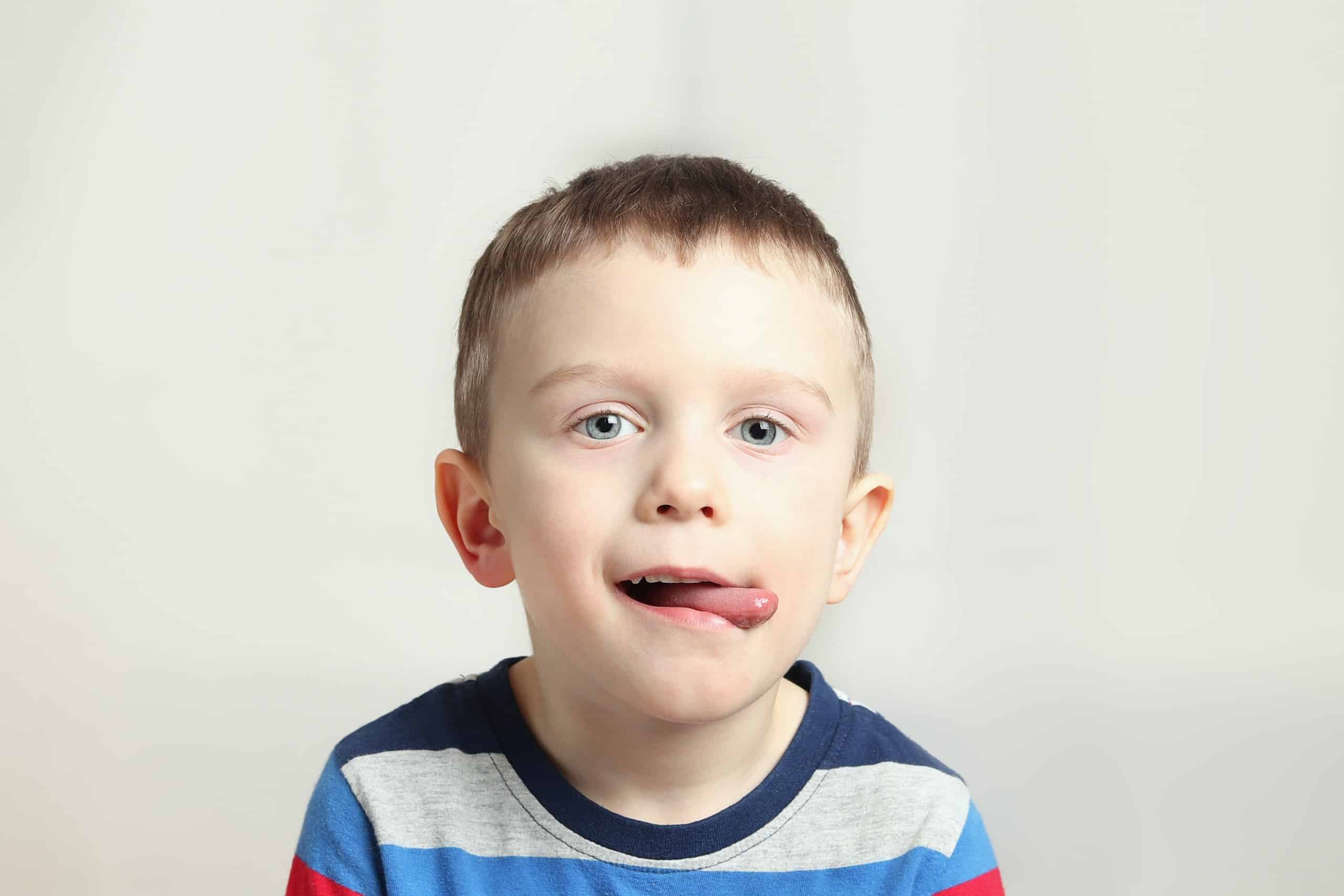 Boy, kid performs articulation exercises for the tongue, correct pronunciation, vocals, dental concept, speech therapy boy performs articulation tongue exercise