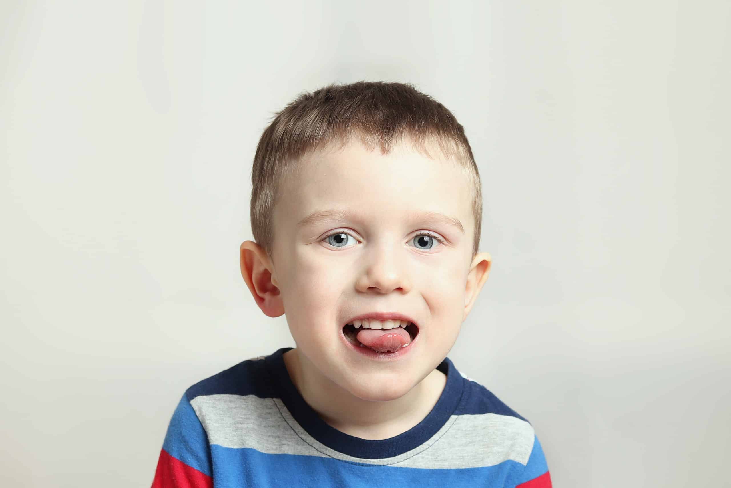 Boy, kid performs articulation exercises for the tongue, correct pronunciation, vocals, dental concept, speech therapy boy performs articulation tongue exercise